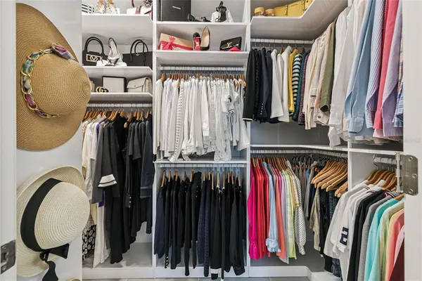 a view of walk in closet with clothes and shoes