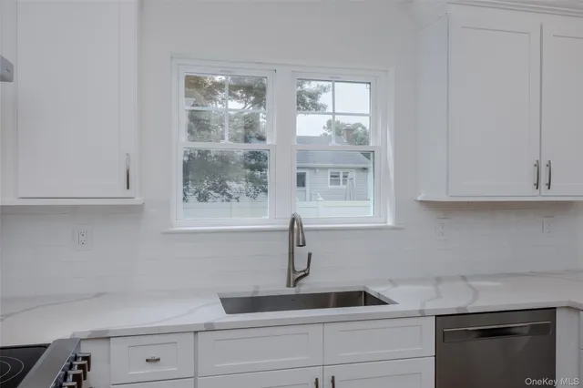 a kitchen with white cabinets and a window