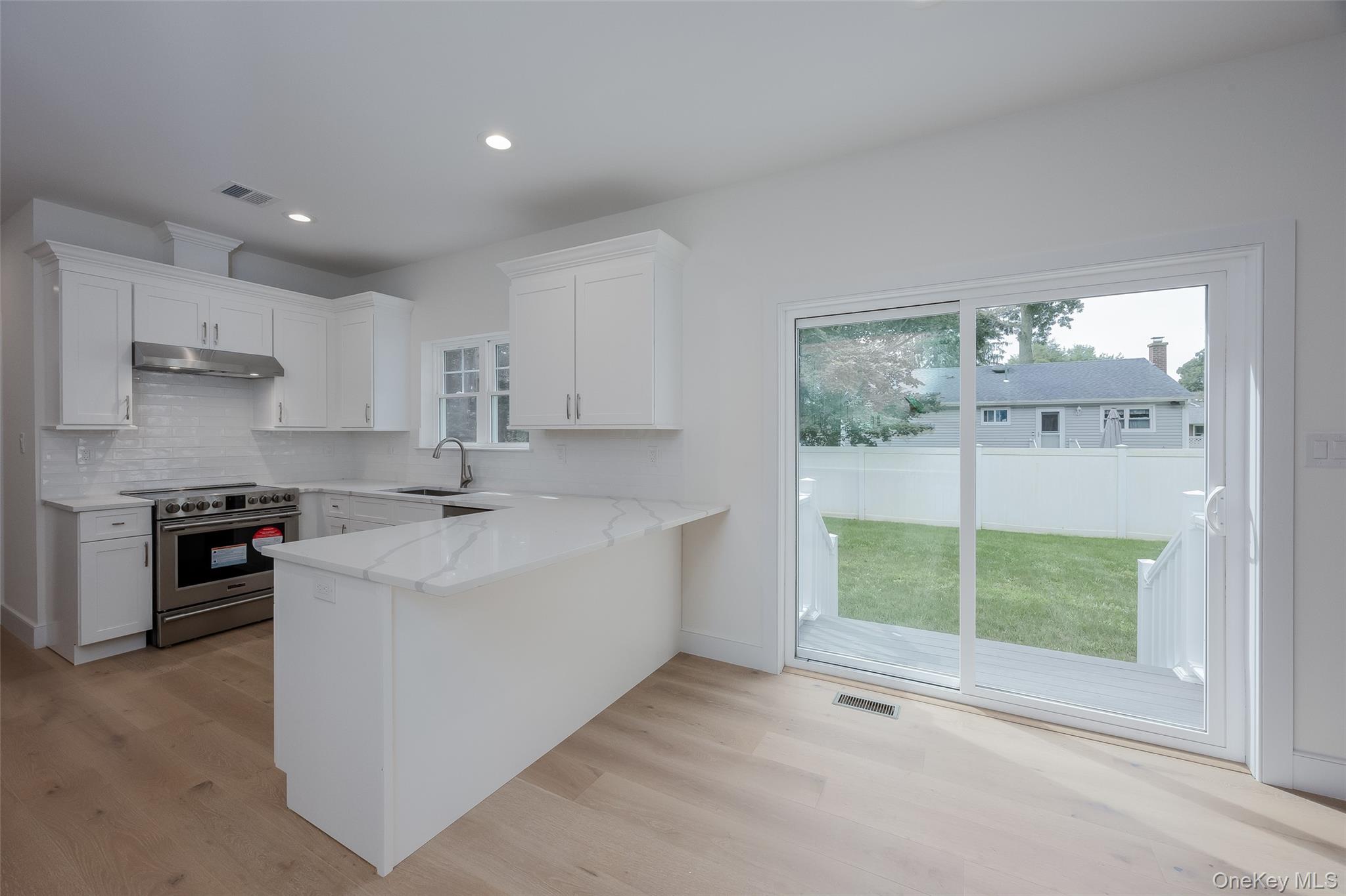 40 Zenith Road Rocky Point, NY 11778 - Photo 15 of 38 a large white kitchen with a sink stainless steel appliances and cabinets