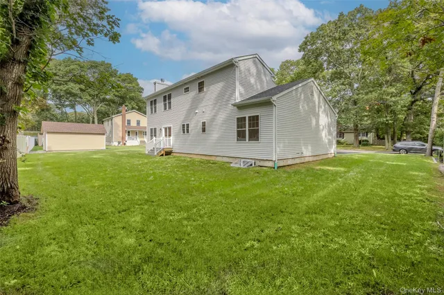a house that is sitting in the grass with tress in the background