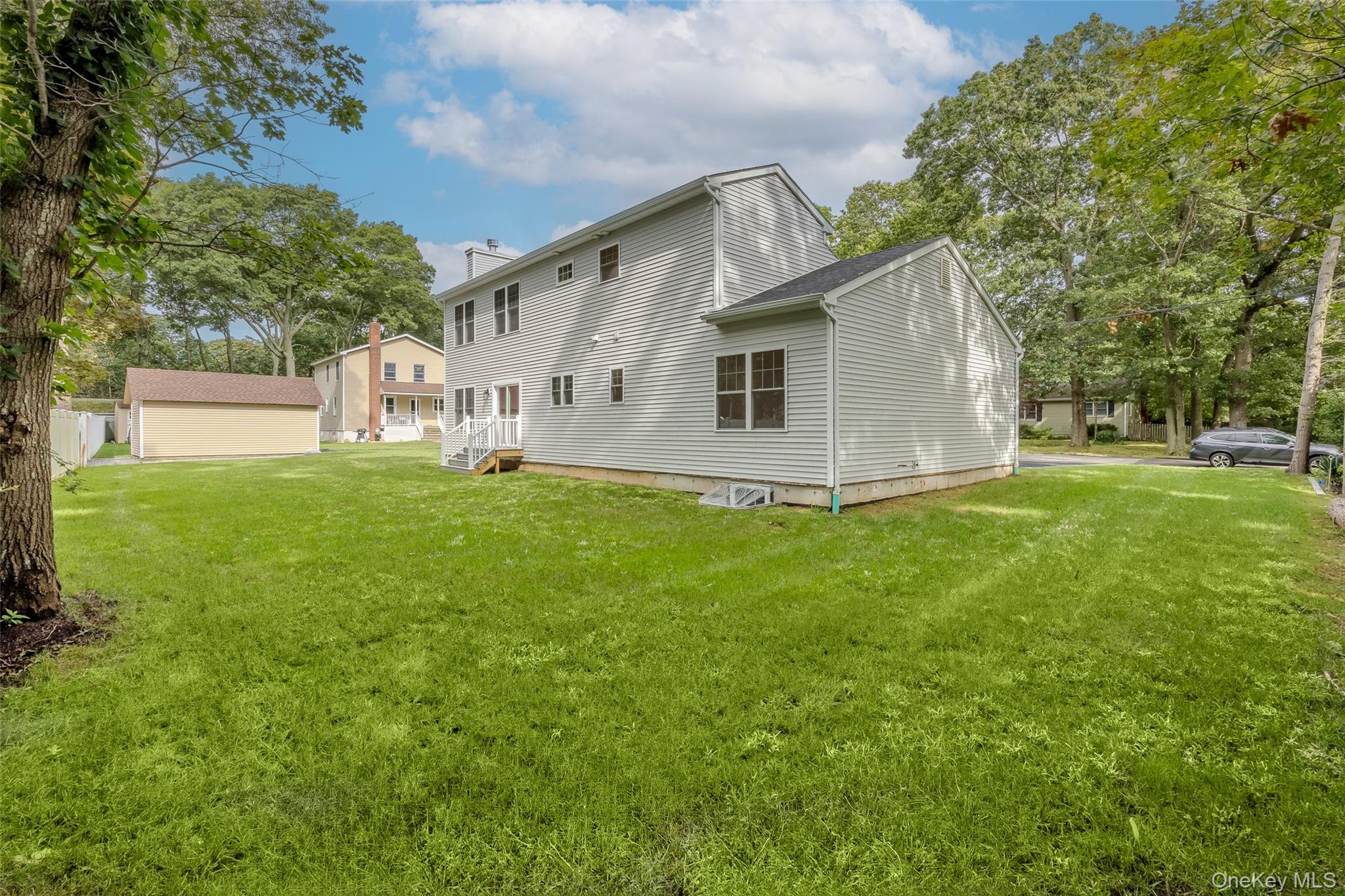 40 Zenith Road Rocky Point, NY 11778 - Photo 3 of 38 a house that is sitting in the grass with tress in the background