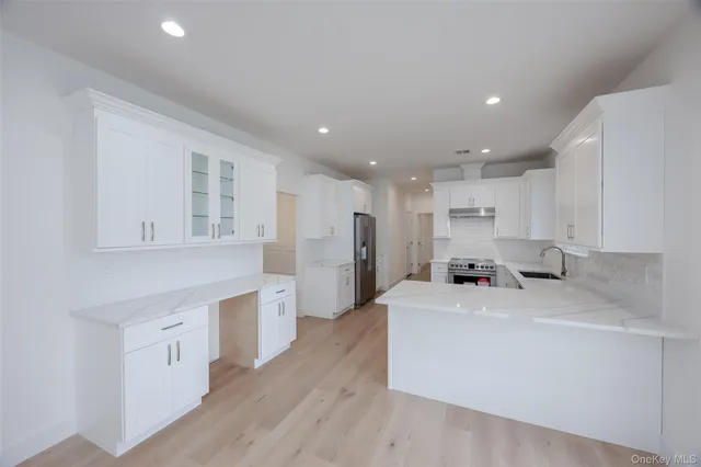 a kitchen with a sink a stove a refrigerator and white cabinets