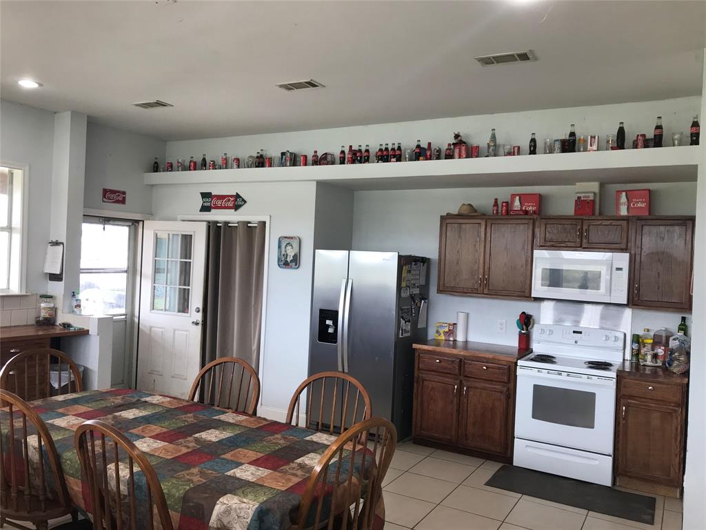 1100 East Rabbit Cove Road Quinlan, TX 75474 - Photo 2 of 18 Kitchen with white appliances, light tile patterned floors, and dark brown cabinetry