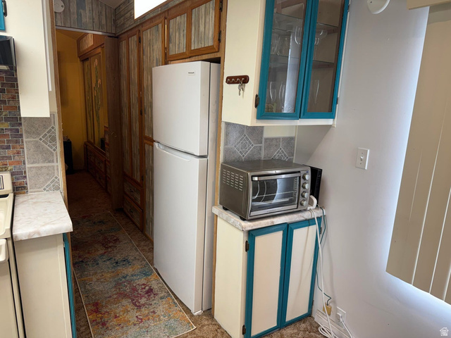 1225 North Dixie Downs Road, Unit 100 St. George, UT 84770 - Photo 12 of 22 Kitchenette featuring cream cabinetry with teal trim, a white refrigerator, and glass-front upper cabinets