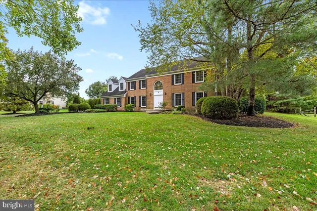 a front view of a house with garden and trees