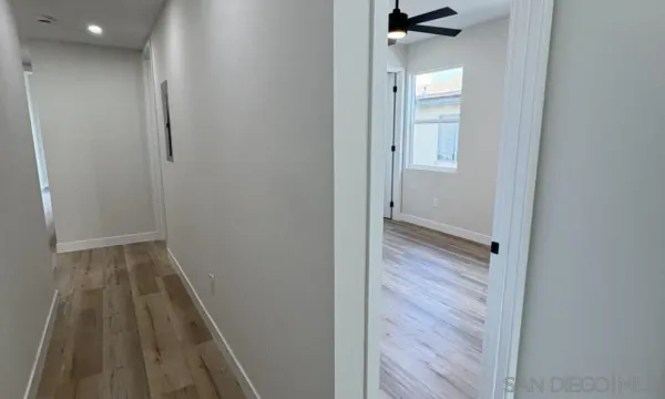 an empty room with wooden floor chandelier fan and windows
