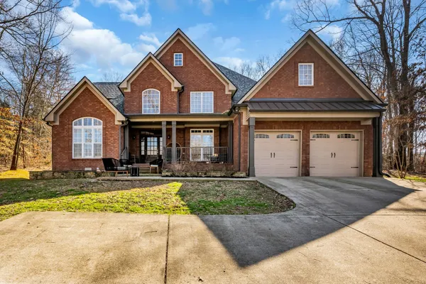 a front view of a house with yard and parking