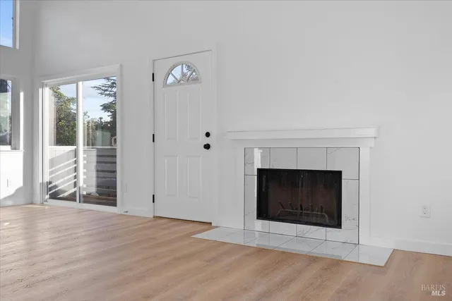 an empty room with wooden floor fireplace and windows
