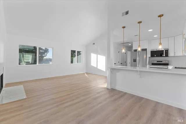 a kitchen with stainless steel appliances granite countertop a stove a sink and white cabinets with wooden floor