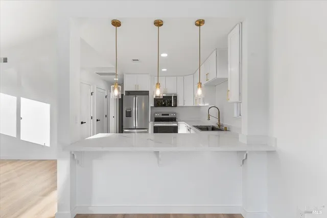 a view of a kitchen with kitchen island white cabinets and stainless steel appliances