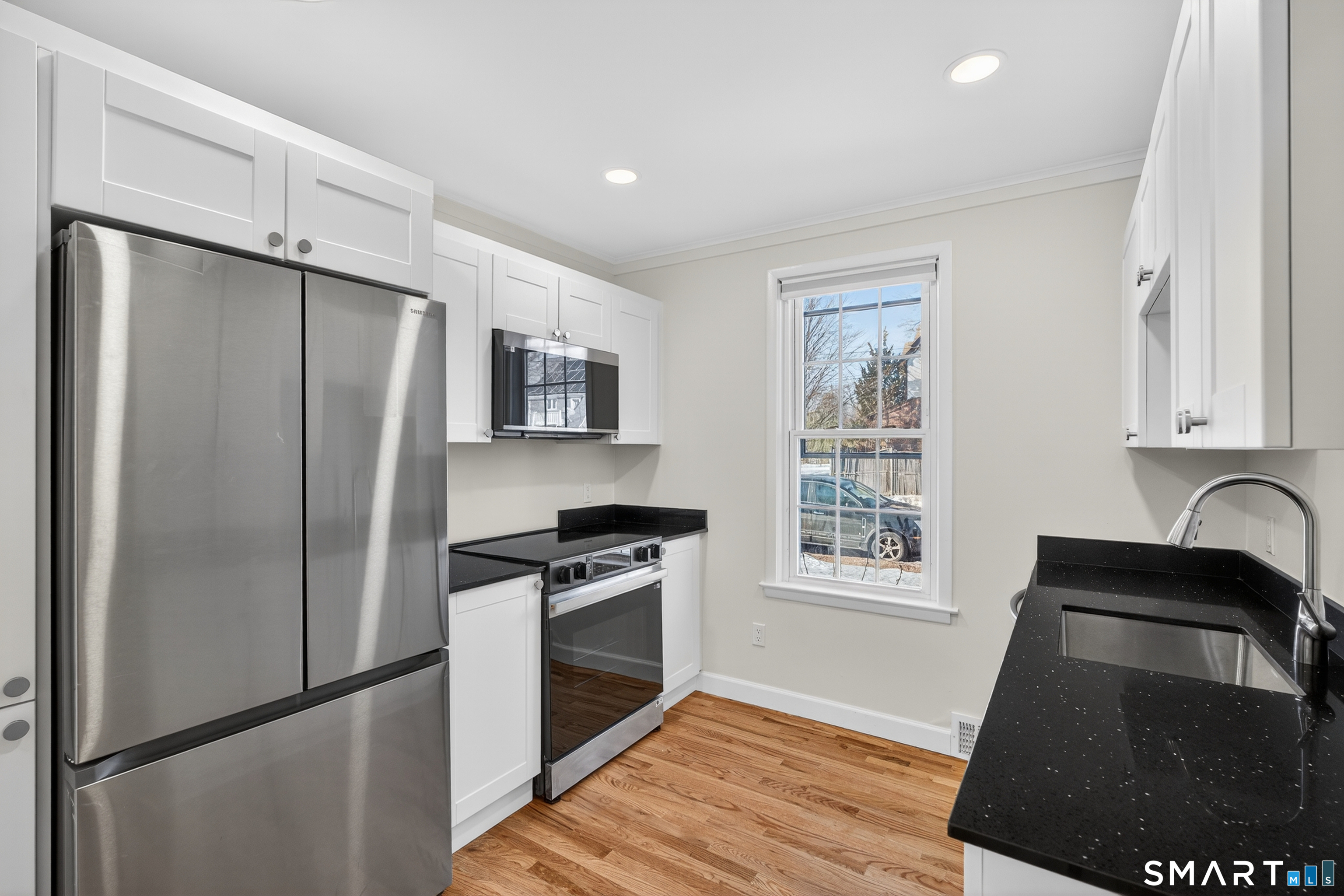 a kitchen with granite countertop stainless steel appliances a refrigerator a stove a sink and a window