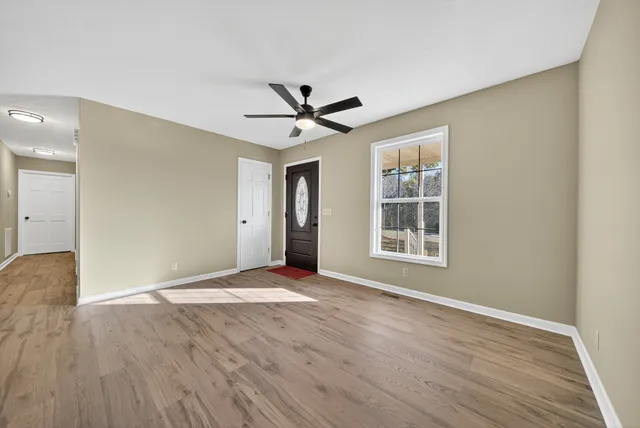 a view of empty room with wooden floor and fan