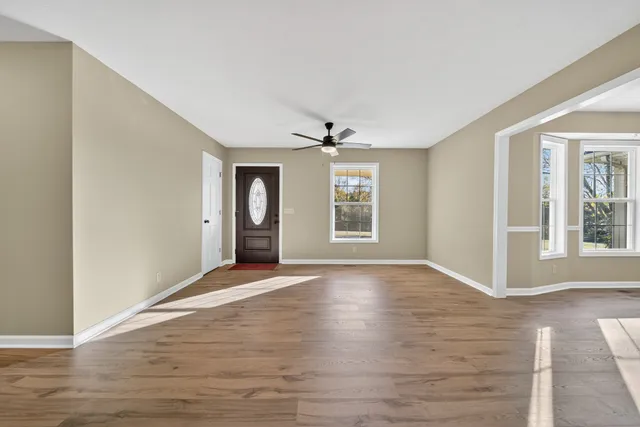 a view of empty room with wooden floor and ceiling fan