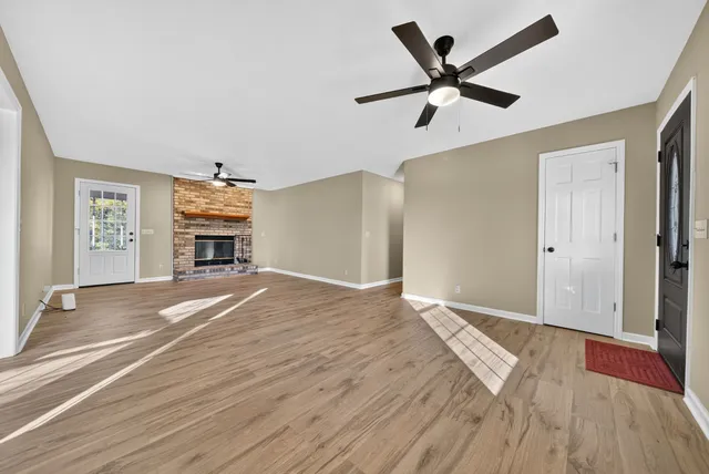 a view of an empty room with wooden floor fireplace and a window