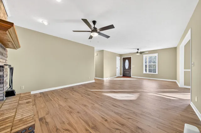 an empty room with wooden floor fan and windows
