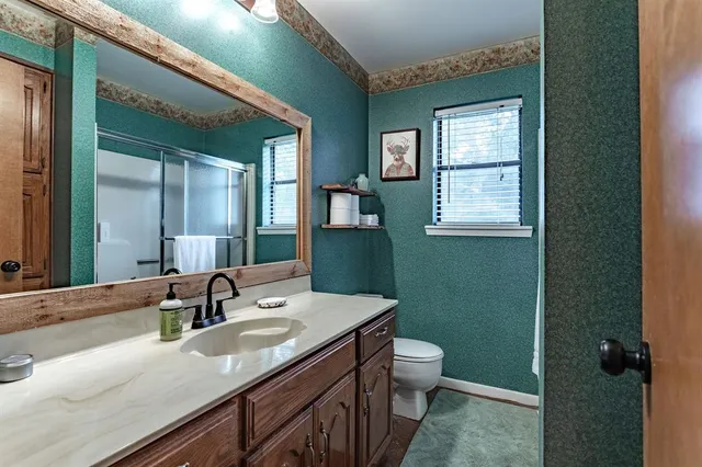a bathroom with a granite countertop sink a toilet and a mirror