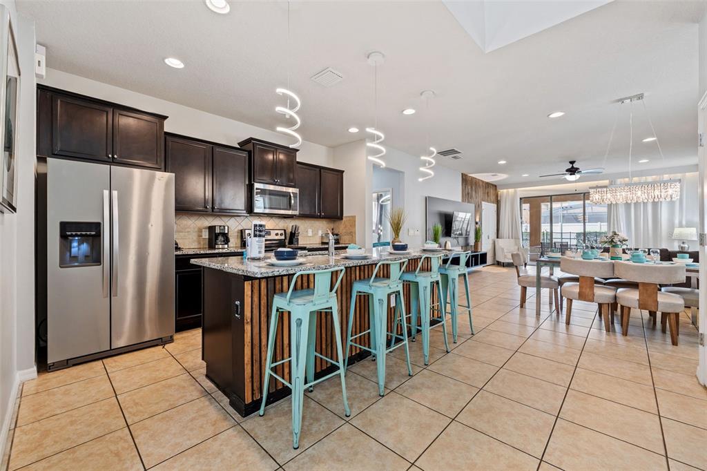 2108 Morocco Way Kissimmee, FL 34747 - Photo 20 of 57 a open kitchen with kitchen island granite countertop a refrigerator and a sink