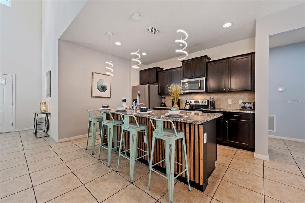 2108 Morocco Way Kissimmee, FL 34747 - Photo 21 of 57 a kitchen with stainless steel appliances kitchen island granite countertop a stove a sink and a refrigerator