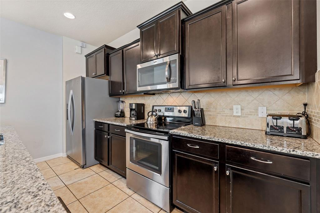 2108 Morocco Way Kissimmee, FL 34747 - Photo 23 of 57 a kitchen with stainless steel appliances granite countertop a stove a refrigerator and a granite counter tops