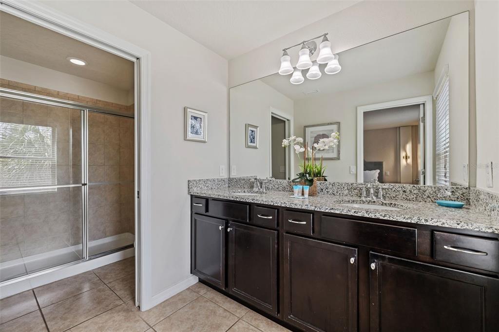 2108 Morocco Way Kissimmee, FL 34747 - Photo 39 of 57 a bathroom with a granite countertop sink a large mirror and a shower