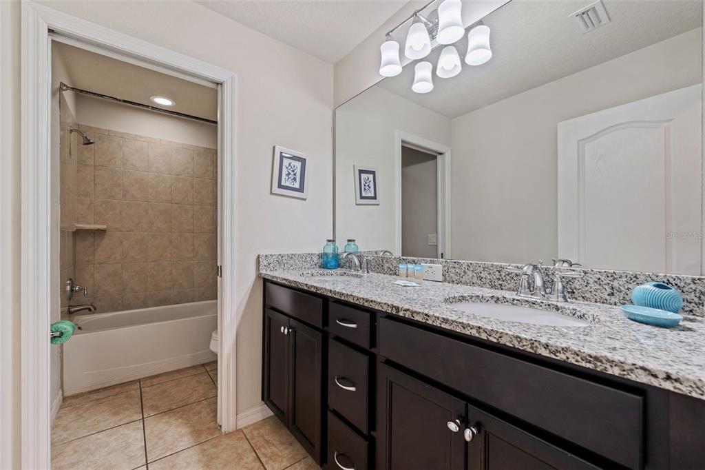 2108 Morocco Way Kissimmee, FL 34747 - Photo 41 of 57 a bathroom with a granite countertop sink a toilet a mirror and shower
