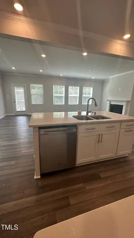 a kitchen with stainless steel appliances granite countertop a sink dishwasher a stove and a refrigerator with wooden floor