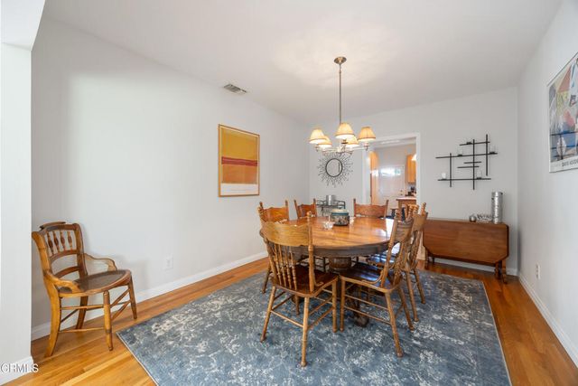 a kitchen with stainless steel appliances a dining table chairs refrigerator and sink