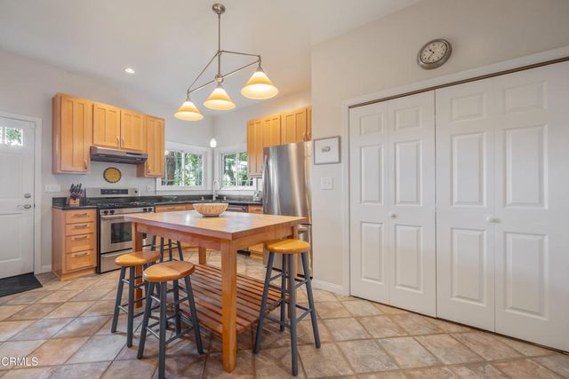 a kitchen with stainless steel appliances kitchen island granite countertop wooden cabinets refrigerator and stove