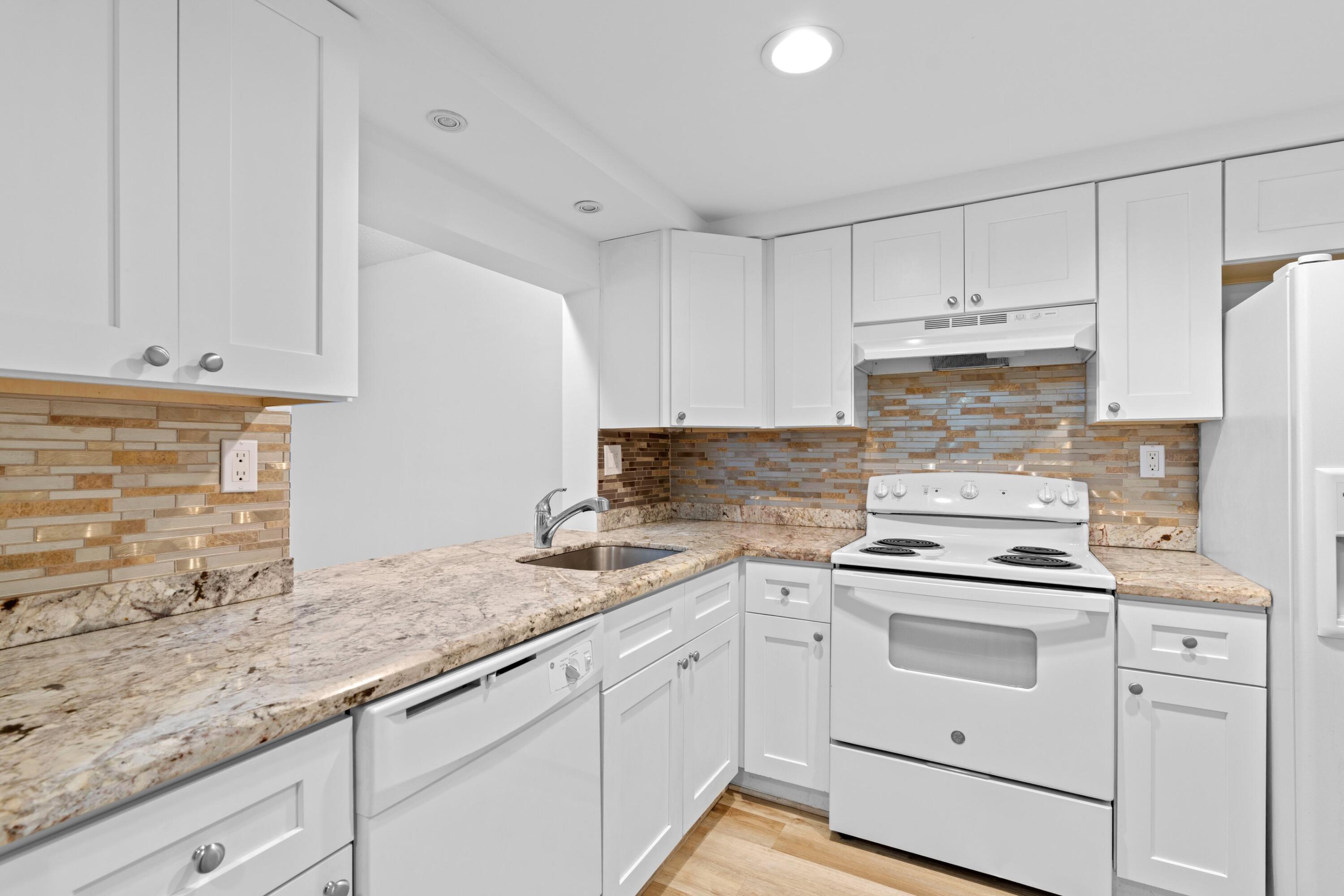 3710 North Pine Island Road, Unit 114 Sunrise, FL 33351 - Photo 8 of 32 a kitchen with granite countertop white cabinets and white appliances