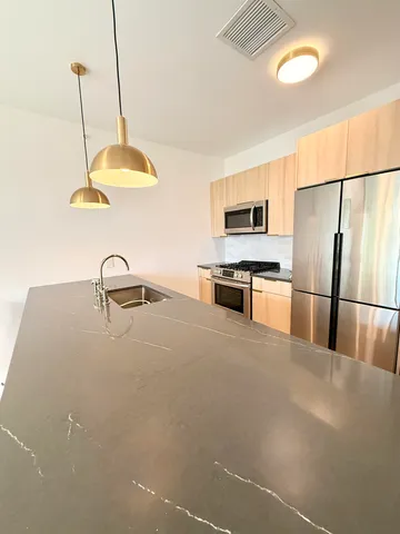 a kitchen with stainless steel appliances granite countertop a refrigerator a stove and a sink