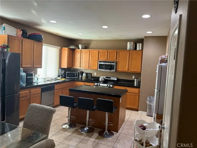 a kitchen with stainless steel appliances granite countertop a refrigerator a sink dishwasher a stove and white countertops with wooden floor