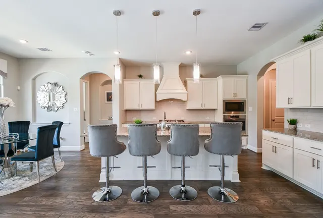 a view of kitchen with stainless steel appliances granite countertop dining room and chairs