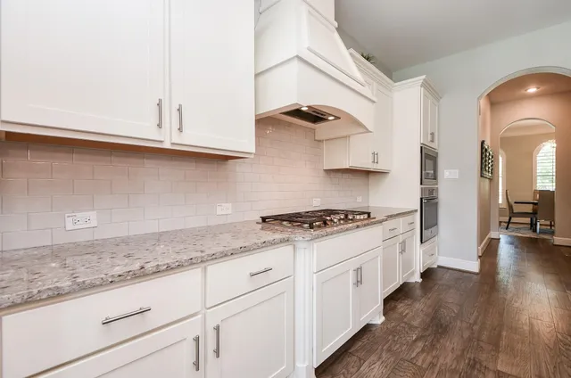 a kitchen with granite countertop white cabinets and white appliances
