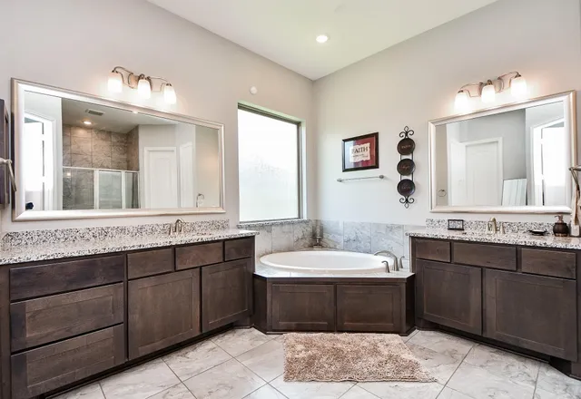 a bathroom with a double vanity sink mirror and bathtub