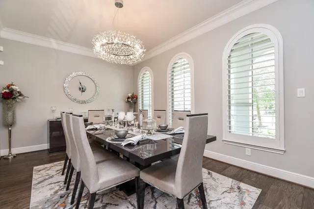 a dining room with wooden floor a chandelier a wooden table and chairs