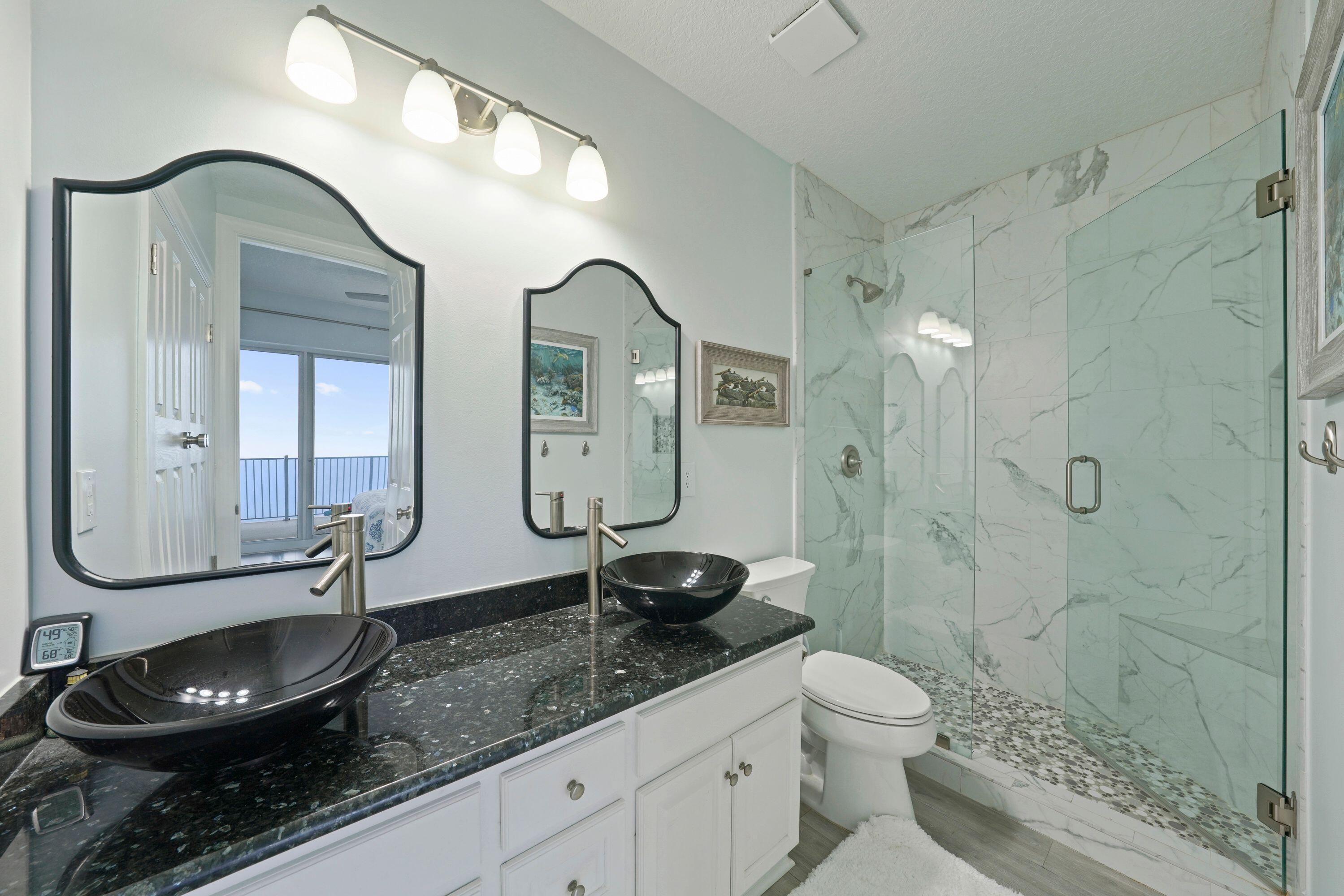 14415 Front Beach Road, Unit 2007 Panama City Beach, FL 32413 - Photo 20 of 26 a bathroom with a granite countertop sink a toilet a mirror and shower