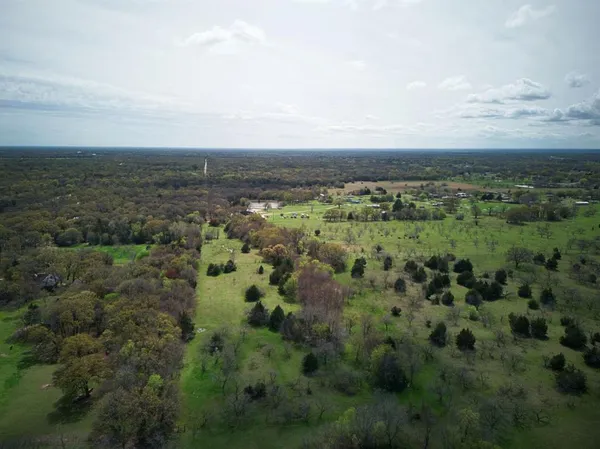 an aerial view of residential houses with outdoor space and trees