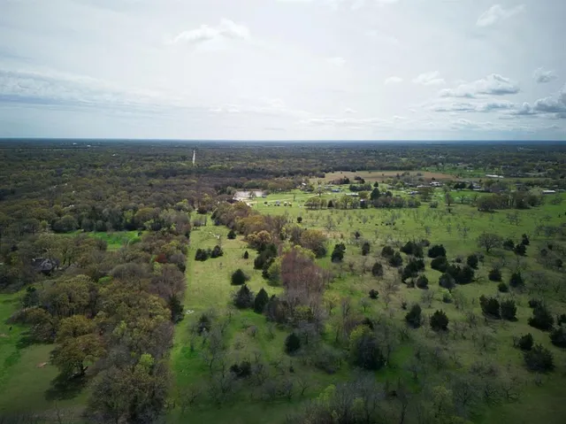 an aerial view of residential houses with outdoor space and trees