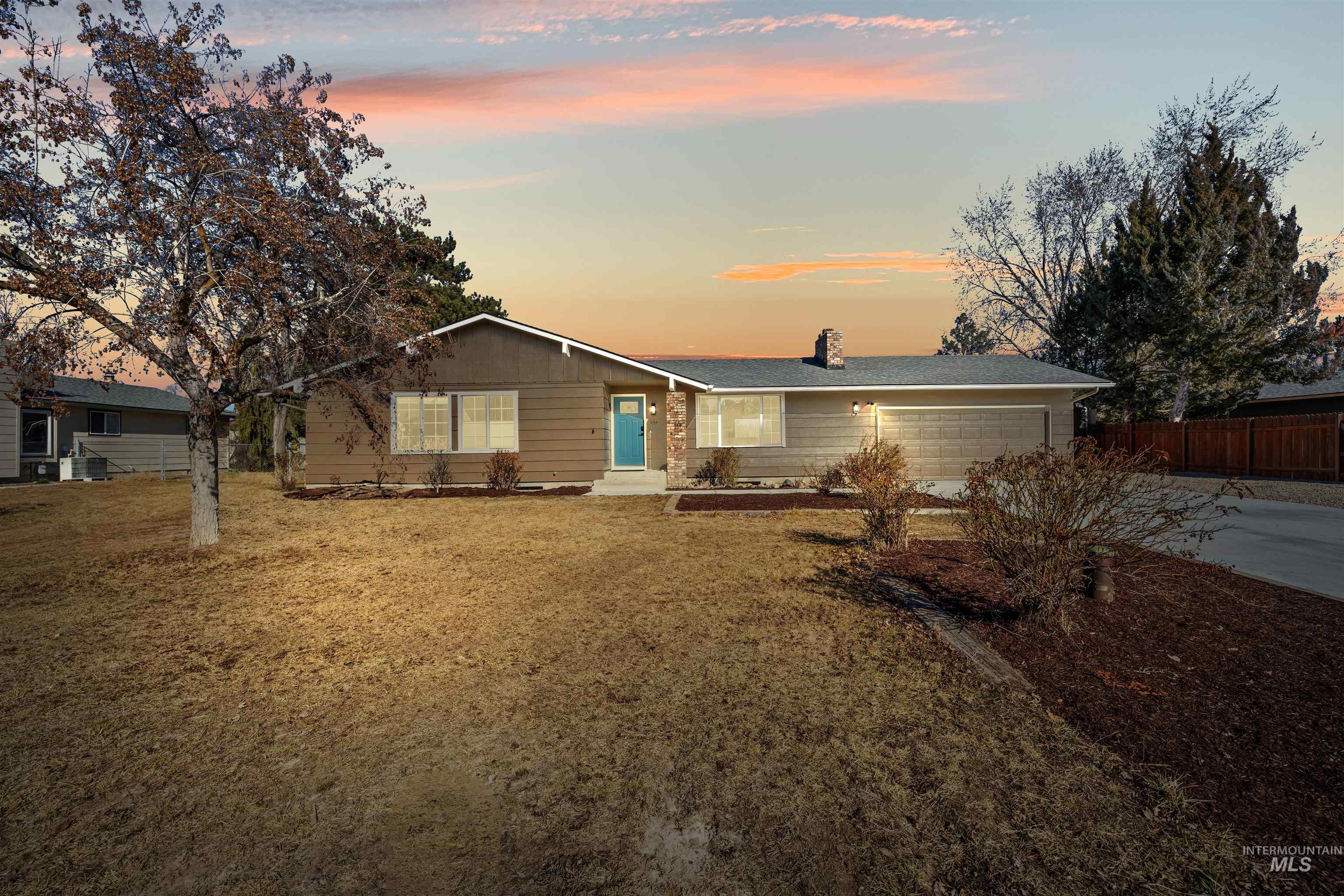 View of front of home featuring concrete driveway, a chimney, and a garage