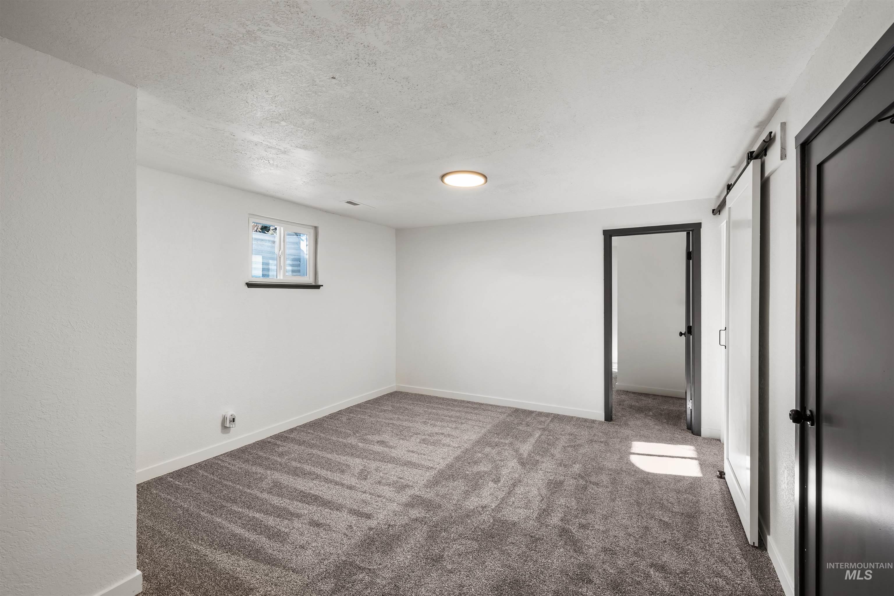 3154 South McCormick Way Boise, ID 83709 - Photo 24 of 50 Unfurnished bedroom with light colored carpet, a textured ceiling, and a barn door