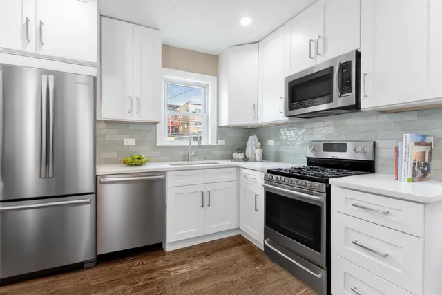 a kitchen with stainless steel appliances white cabinets a stove a sink and a refrigerator