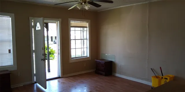 an empty room with wooden floor and windows