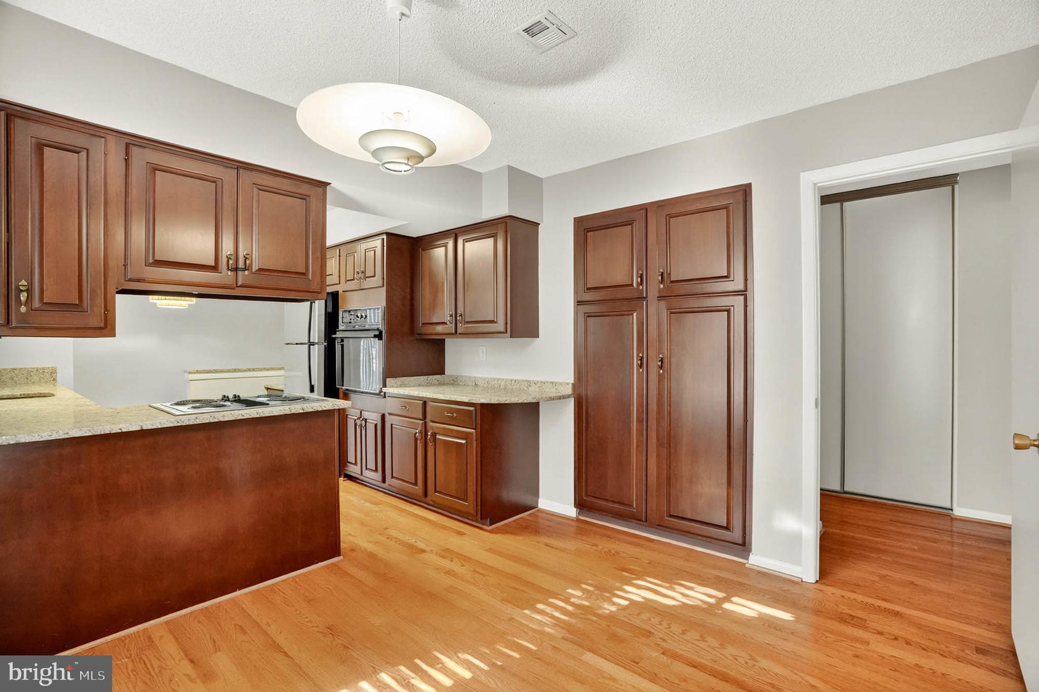 3416 Island Creek Court, Unit 127C Silver Spring, MD 20906 - Photo 16 of 60 a kitchen with granite countertop a refrigerator and wooden cabinets