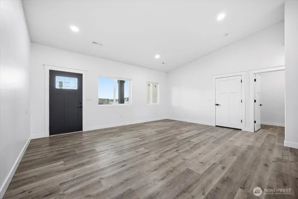 a view of an empty room with wooden floor and windows