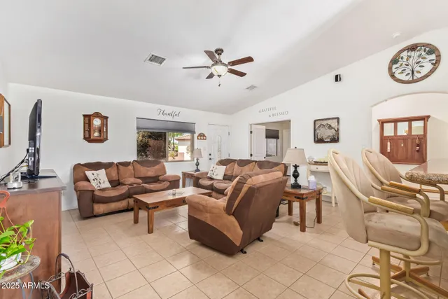 a living room with furniture a clock on wall and a ceiling fan