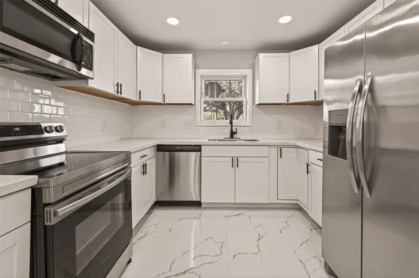 a kitchen with a refrigerator sink and cabinets