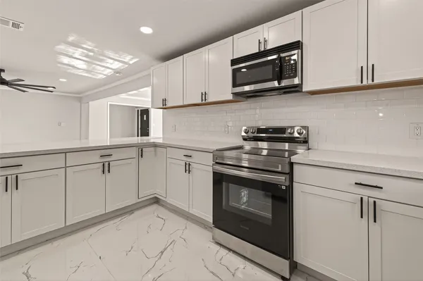 a kitchen with white cabinets and refrigerator