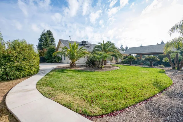a view of a house with a big yard potted plants and large tree
