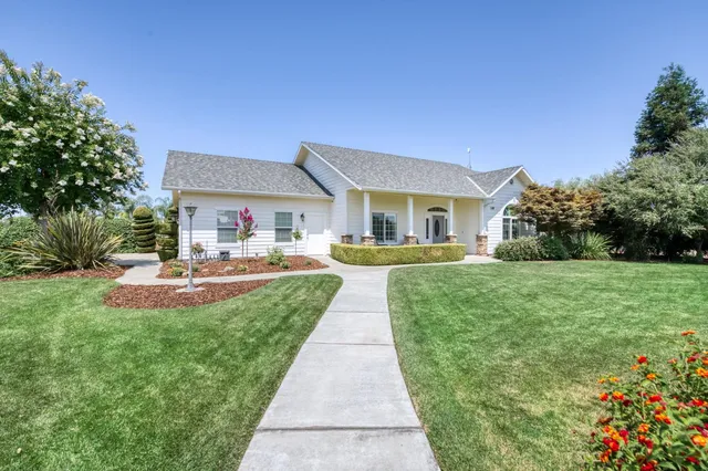 a front view of a house with garden and a bench