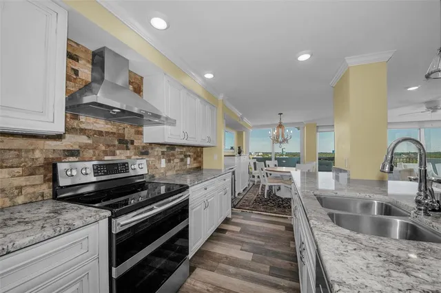 an open kitchen with granite countertop a sink dishwasher a dining table and chairs with wooden floor